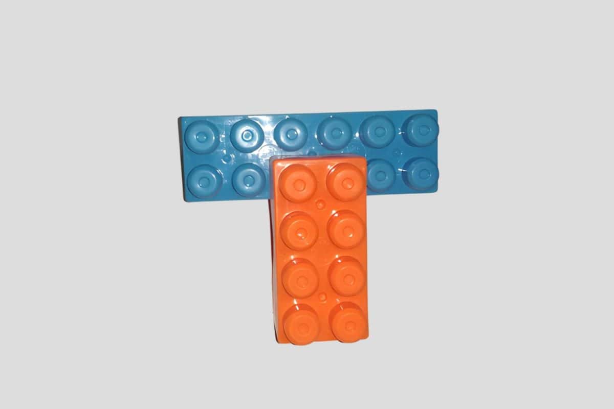 A 3D puzzle of the letter T, made with orange and blue interlocking plastic blocks.