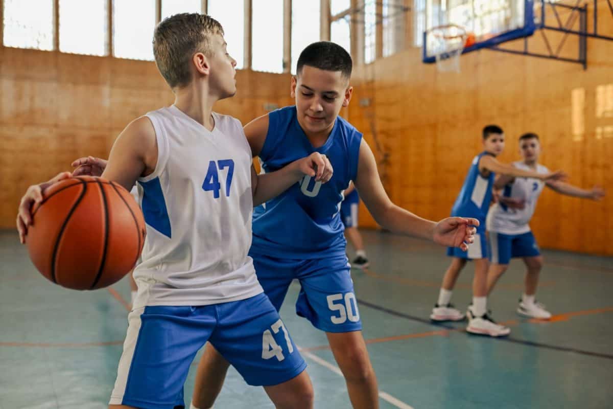 In this image, young kids are engaged in a competitive basketball match, displaying skills and teamwork in the sport, passing the ball