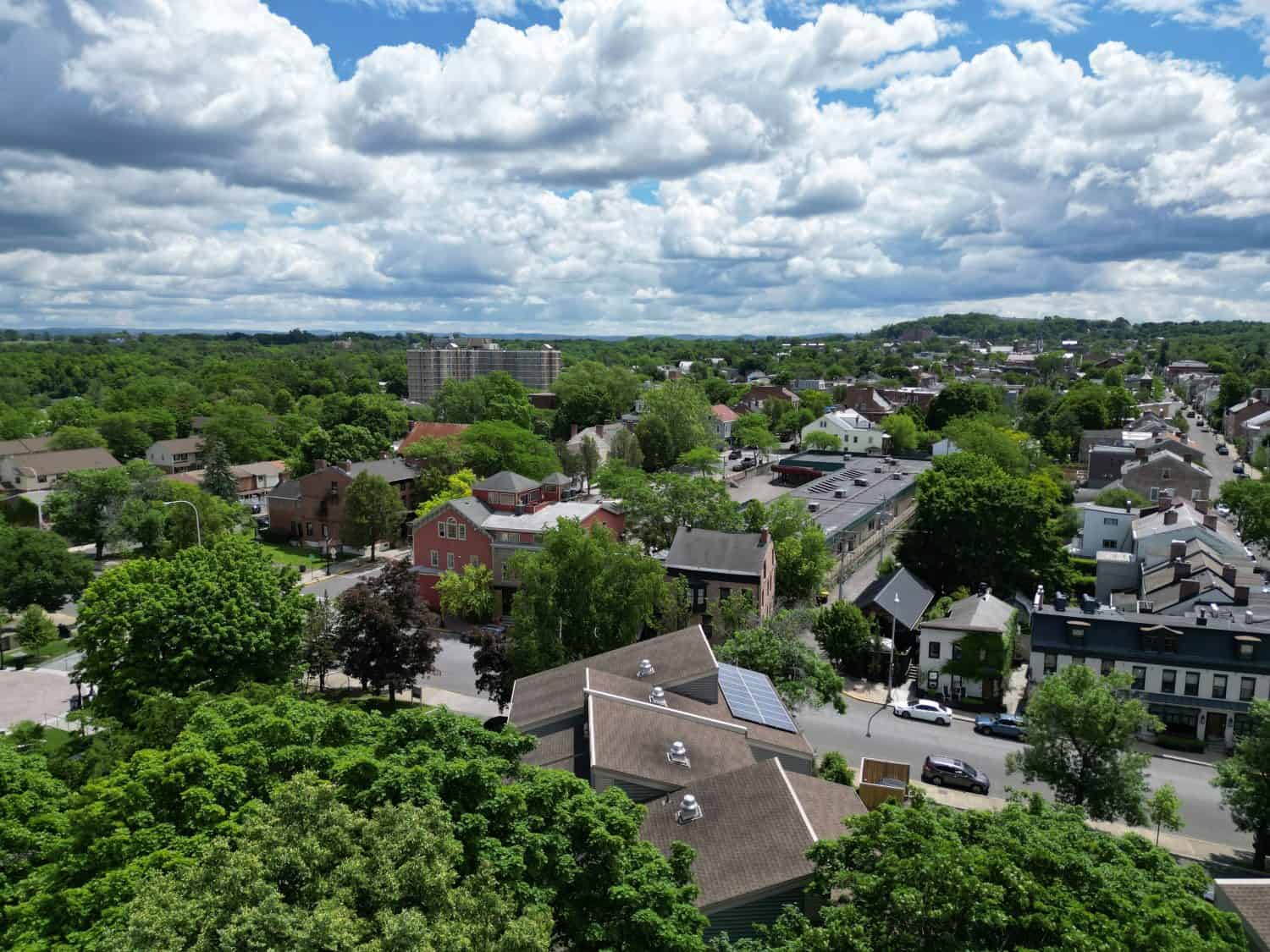 aerial view of hudson, new york (small hudson valley town city downtown historic district) mountains catskills ny travel destination main street with hills clouds cars tree matter