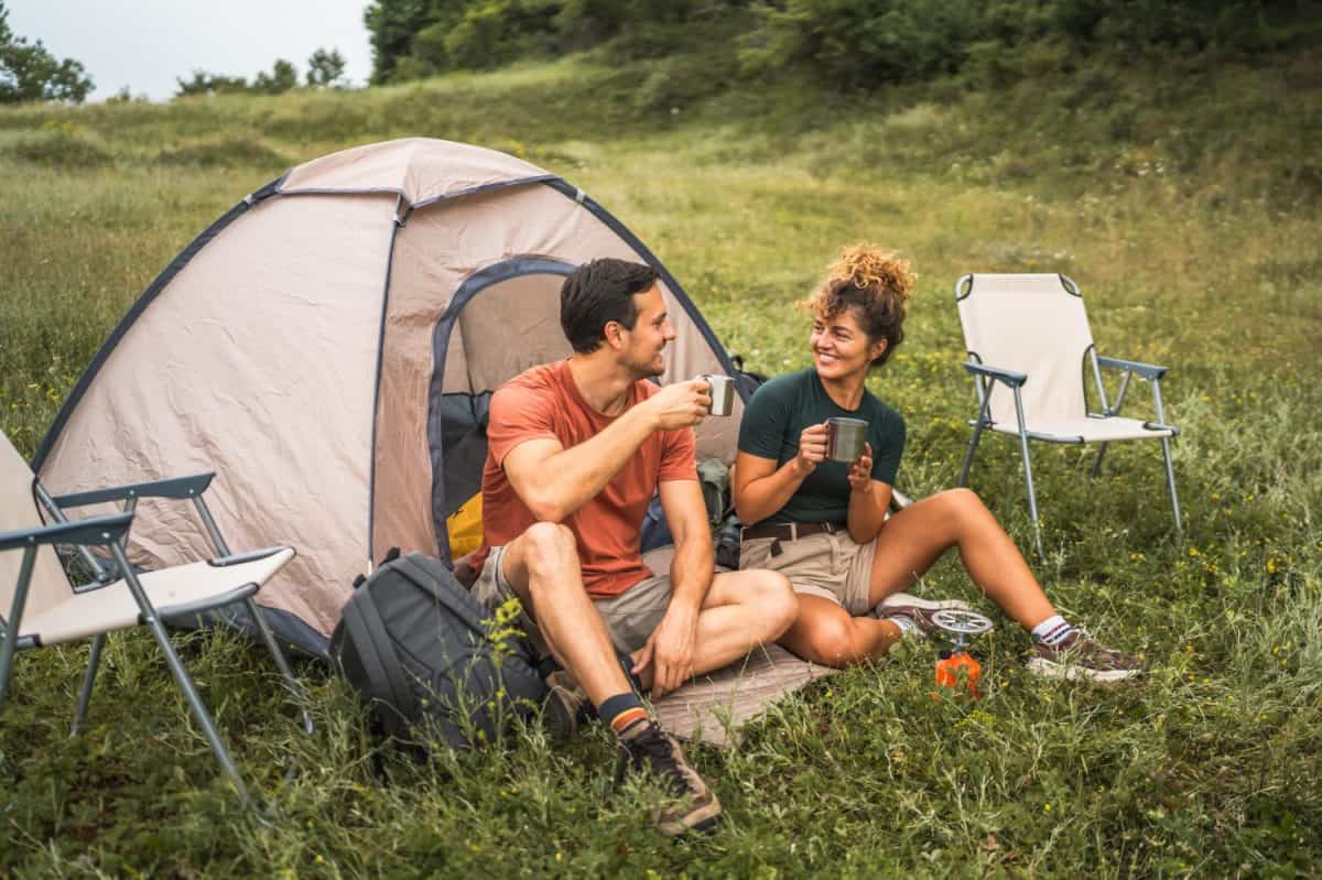 couple in love sit on the grass enjoy camp with coffee and talk. The best U.S. National Parks for camping