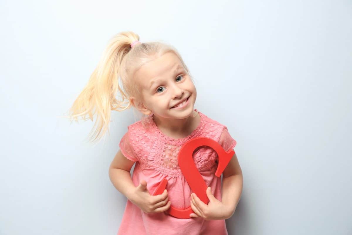 Cute little girl with letter S on light background