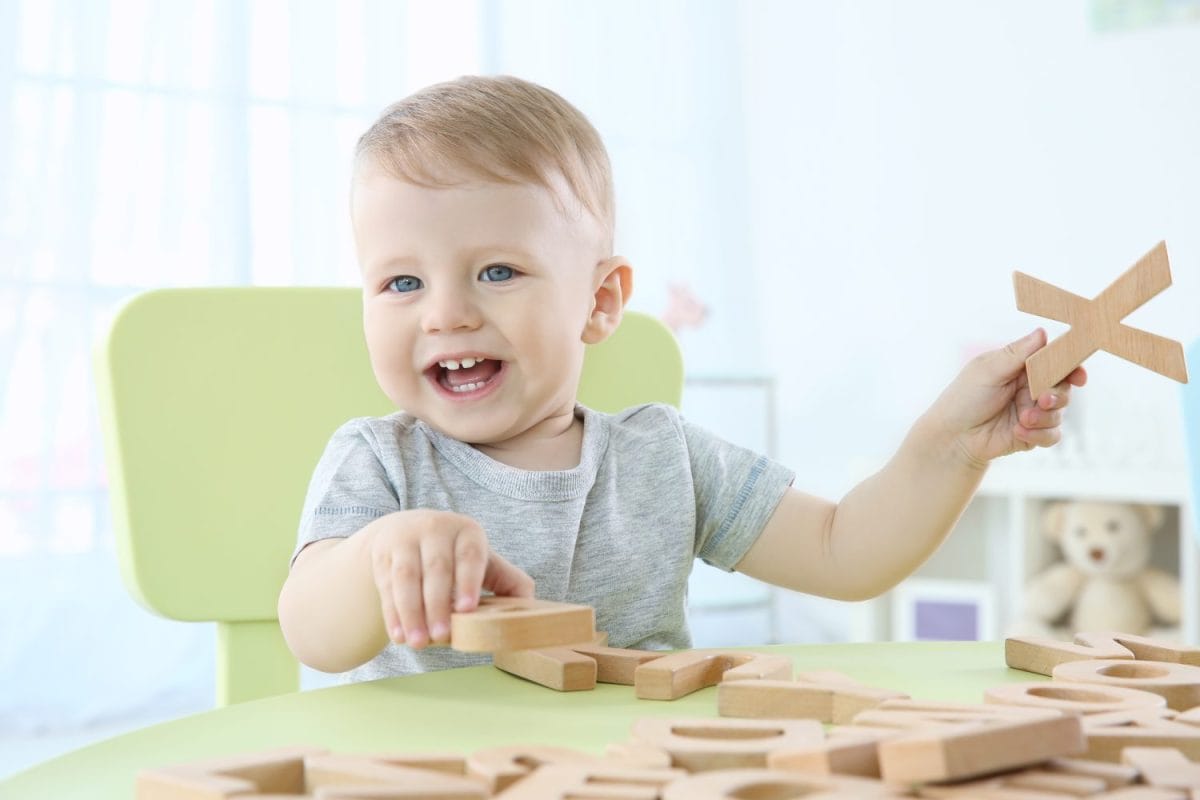 Cute little child playing with letters at home