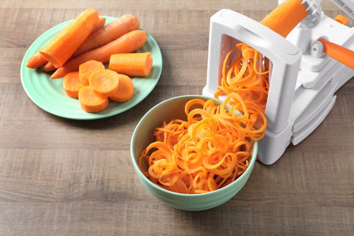 Spiral vegetable slicer with carrot spaghetti on table