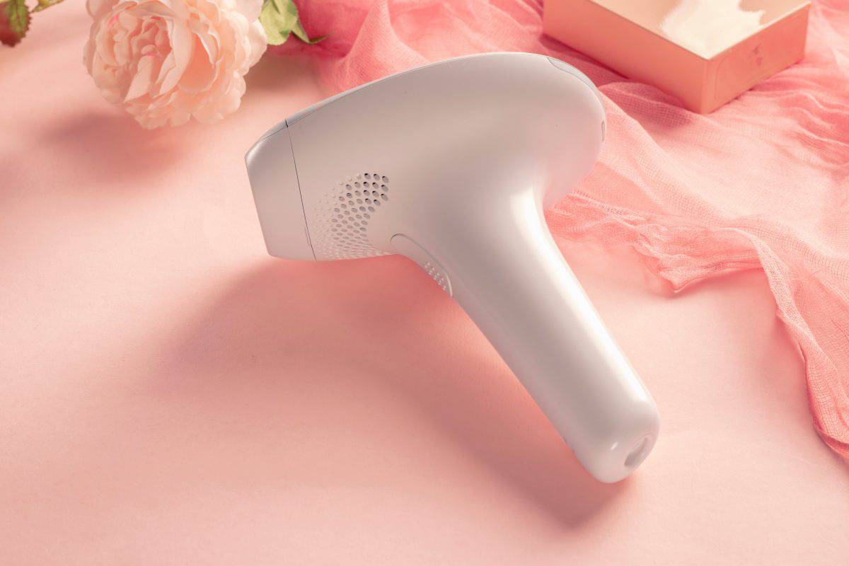 home modern laser epilator. Hair Remover offering Permanently Smooth Skin. Flash Epilator Laser on a pink background. Female blog concept. Photoepilator for home use. High quality photo