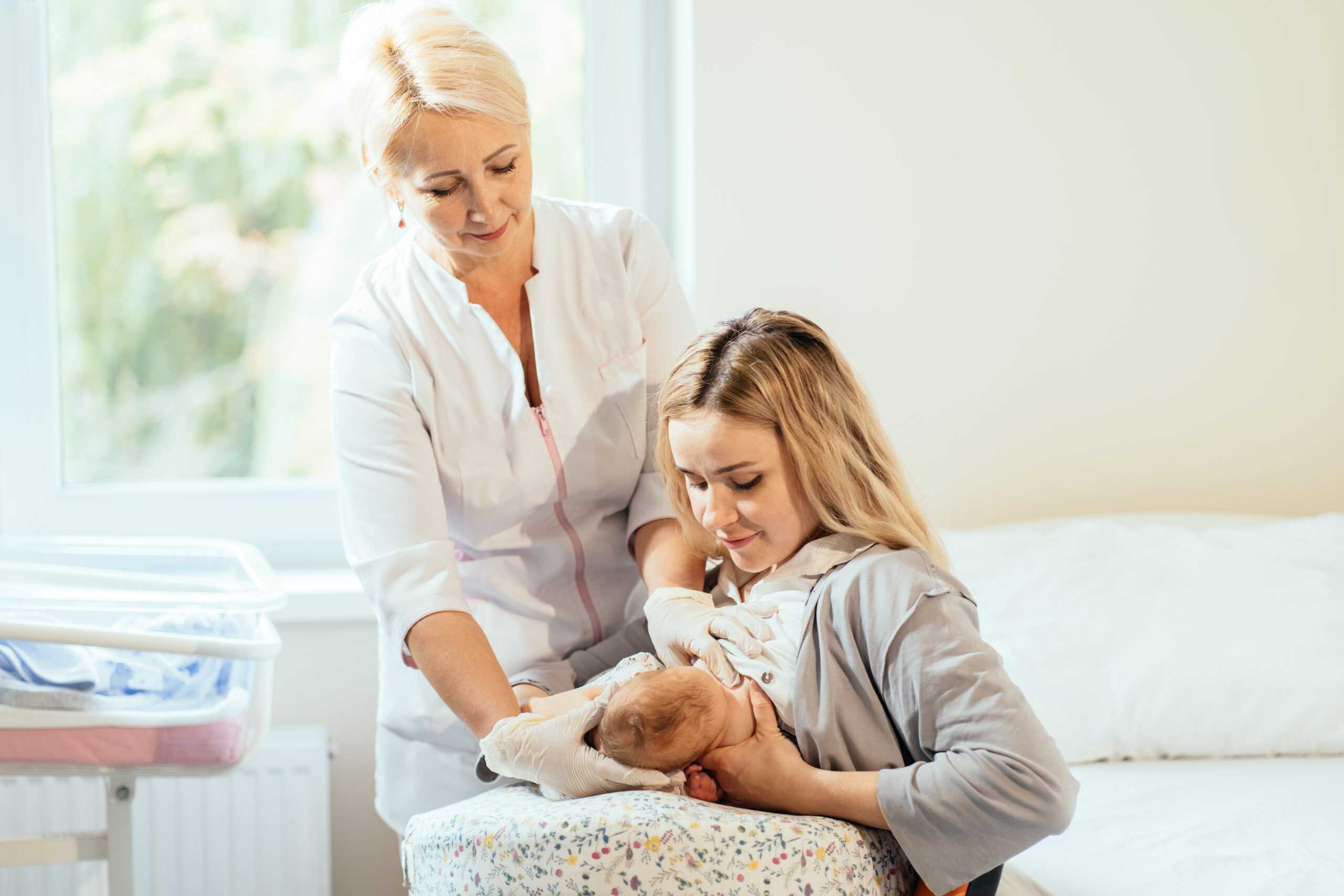 Lactation consultant. Breastfeeding Support and Help for nursing mother. Mother feeding with breast milk at hospital.