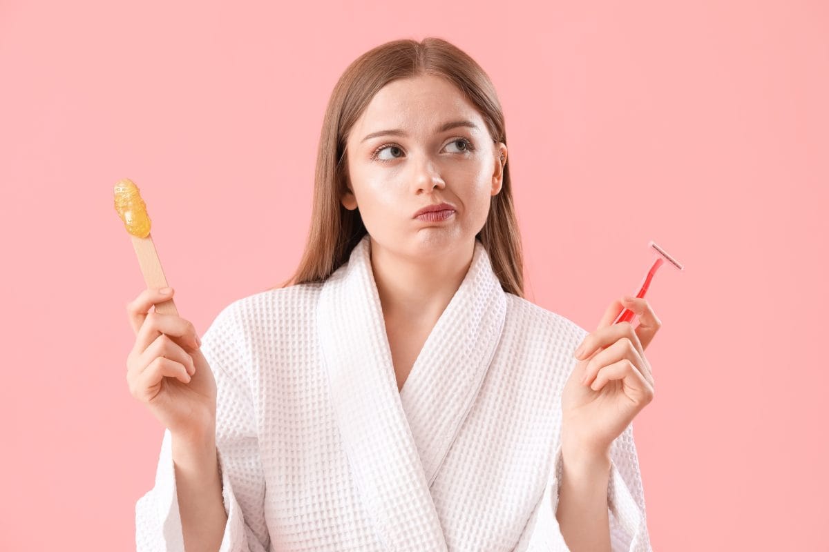 Thoughtful young woman choosing between shaving and sugaring on pink background