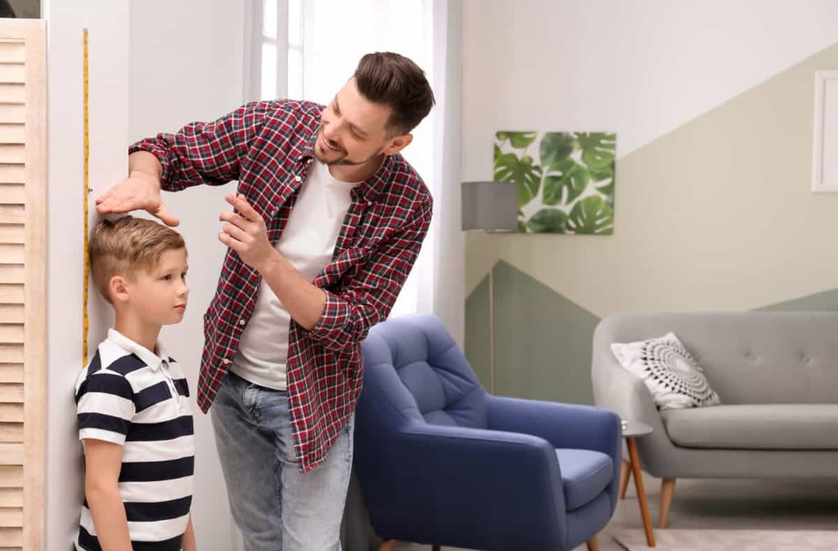 Young man measuring his son's height at homeThese Are the Traits You Got From Your Father