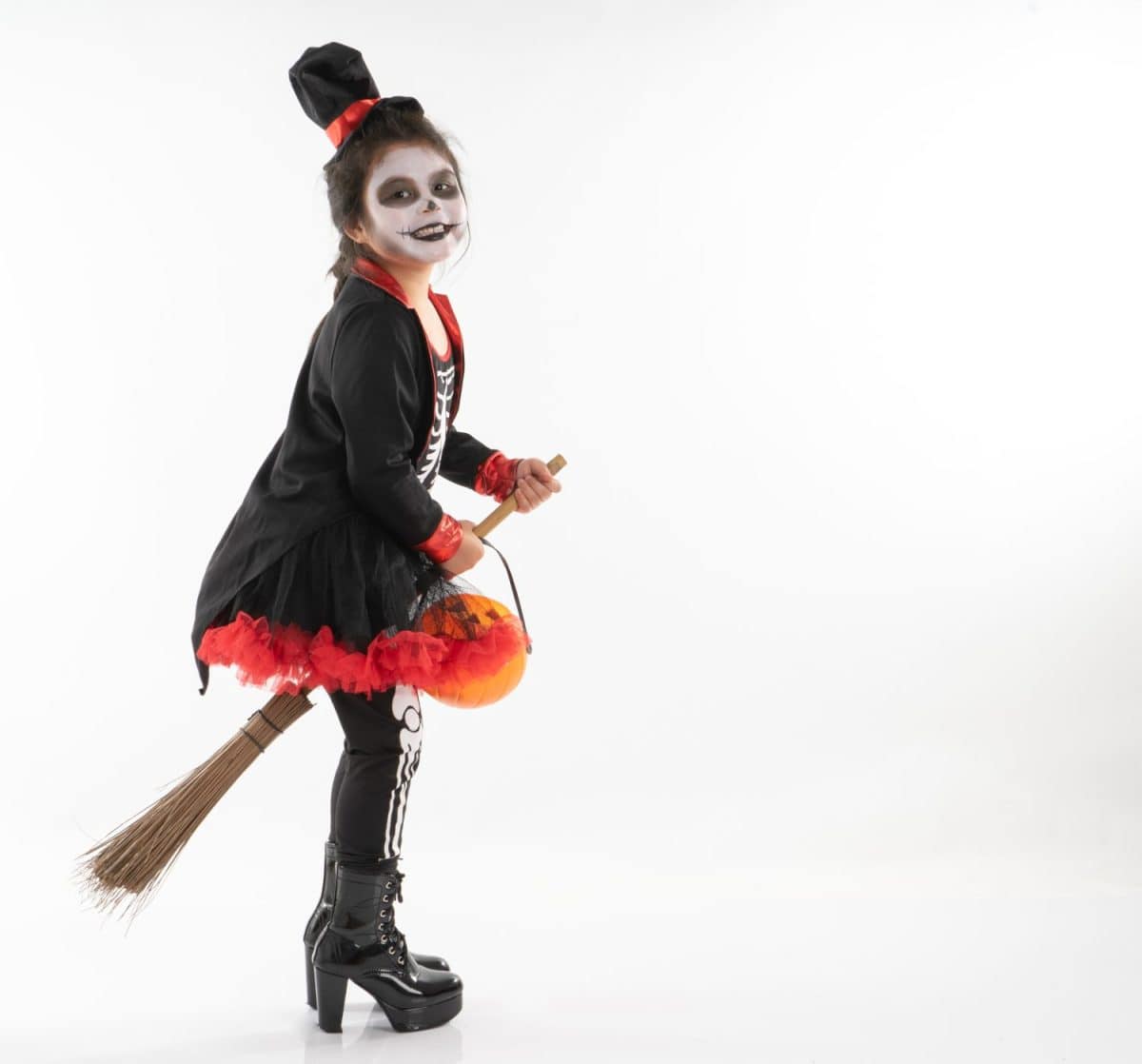 Portrait Asian girl in Halloween costume riding the broom with the pumpkin with isolated background. Happy Halloween festival with cute girl in ghost dress.