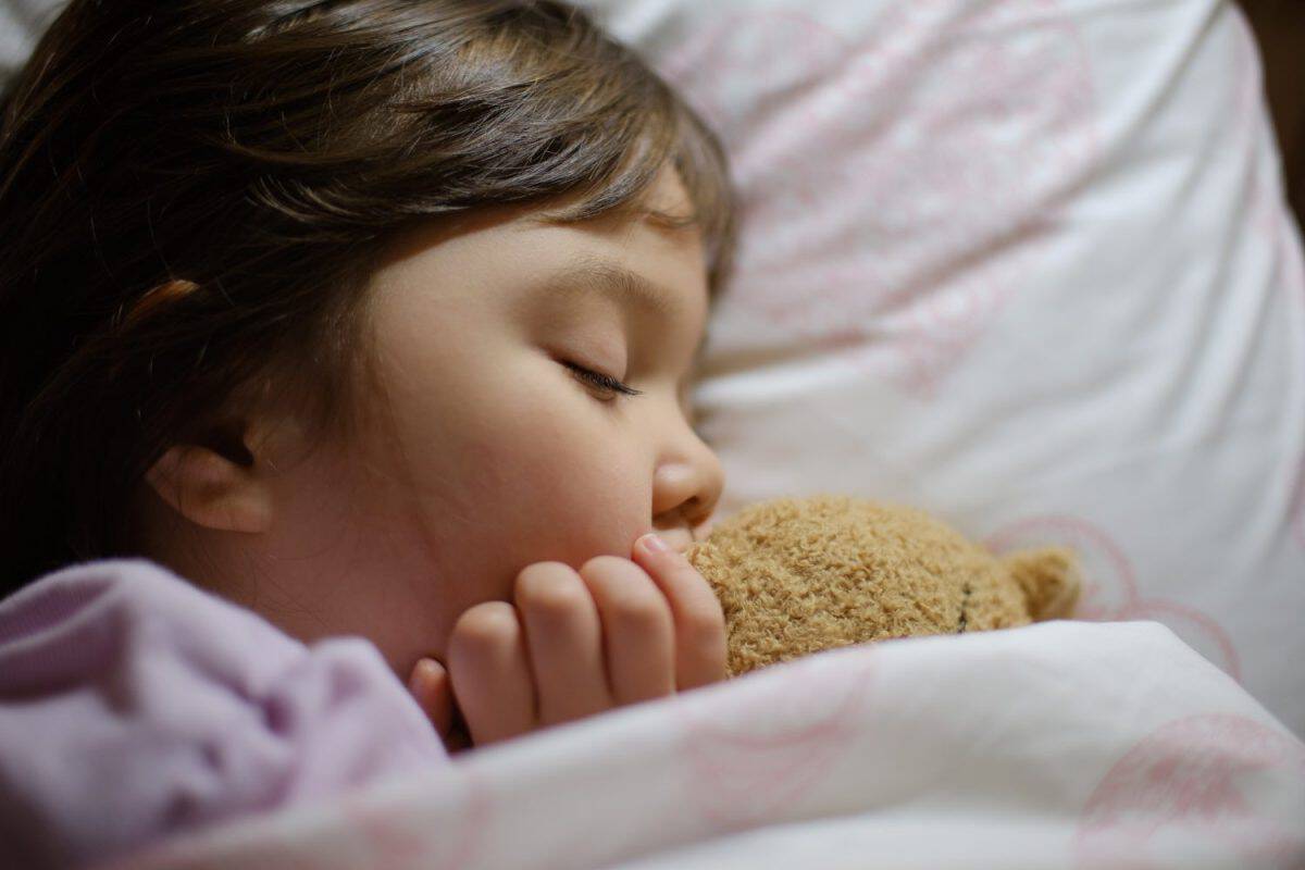 Little girl asleep with her teddy bear.