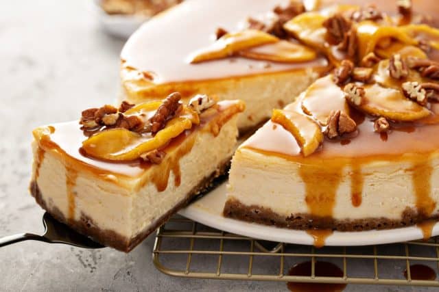 Apple caramel pecan cheesecake with dripping sauce with a slice cut out. Apple Dessert Recipes to Make the Most of This Fall's Harvest