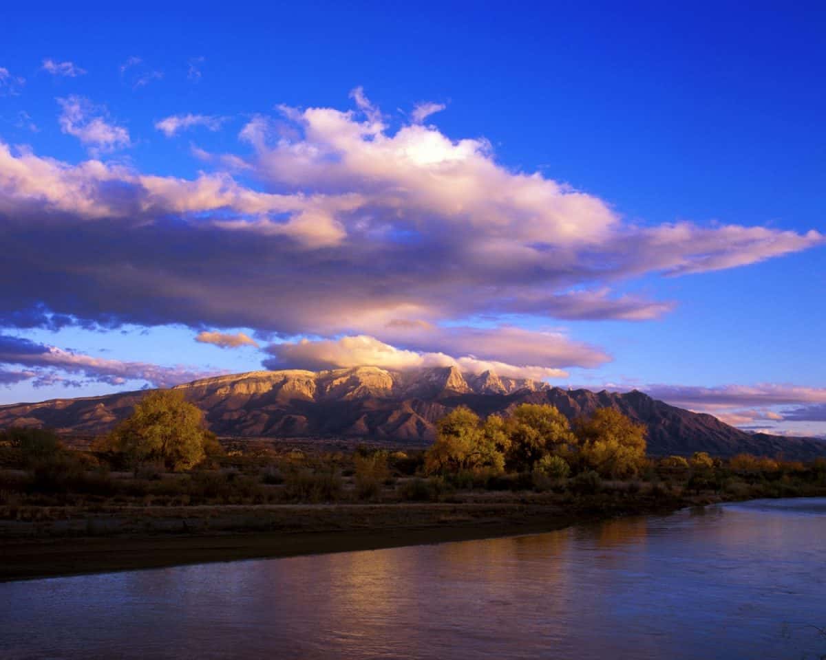 First snow on a clear October evening as the sun was beginning to set. The Rio Grande flowing in the foreground. Sandia Mountains from the town of Bernalillo, New Mexico.