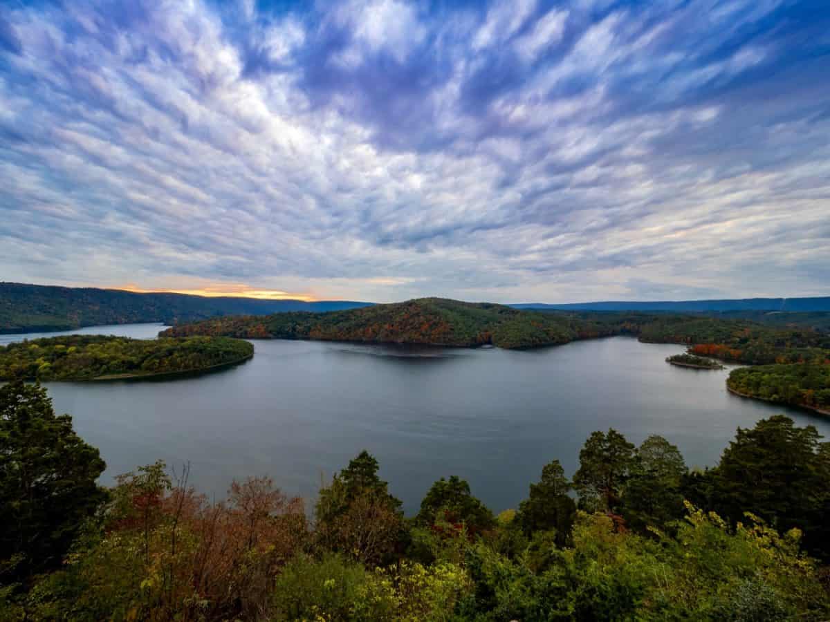 Gorgeous view of Raystown Lake from Hawn’s Overlook near Altoona, Pennsylvania in the fall right before sunset with a view of the dramatic blue sky filled with clouds and pops of pink with foliage.