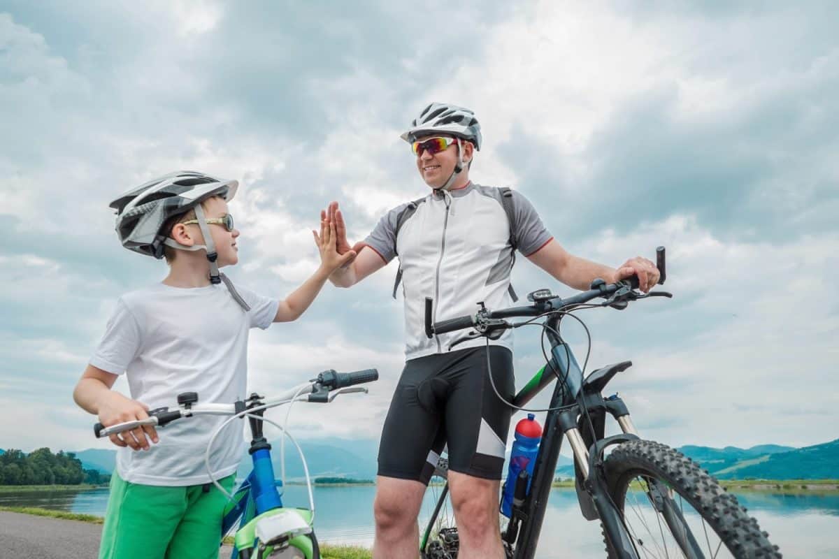 Father and son ride, cycling their bikes together, on sunny day, Happy family in helmets is riding bikes having fun.