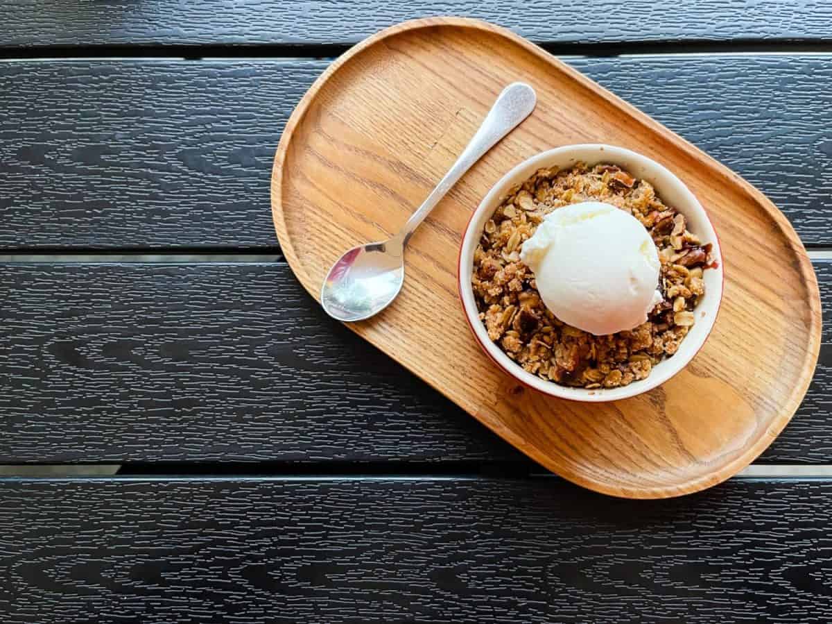 Top view of an apple peach crisp crumble with white ice cream on the wooden tray. Red small plate. Baking. Eating. Eat. Granola. Nuts. Table. Restaurant. Coffee. Desserts. Tasty. Crispy. Crunchy. Apple Dessert Recipes to Make the Most of This Fall's Harvest