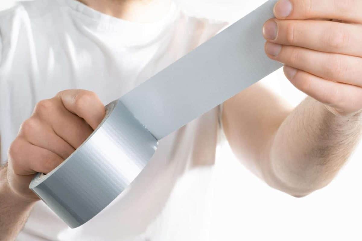 Close up image of man holding adhesive duct tape white background. male hands trying to fix something.