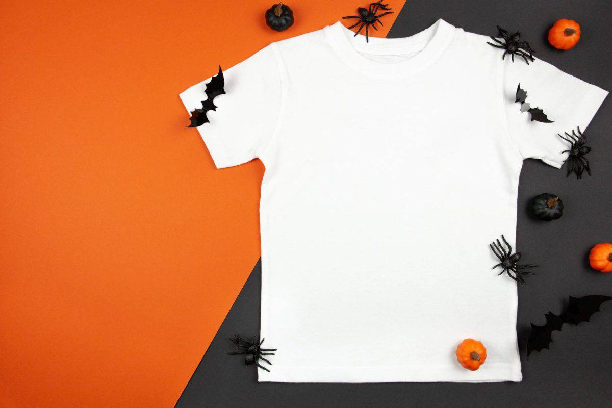 White womens cotton t-shirt halloween mockup with pumpkins, spiders and bats on black orange background. Design t shirt template, print presentation mock up. Top view flat lay.