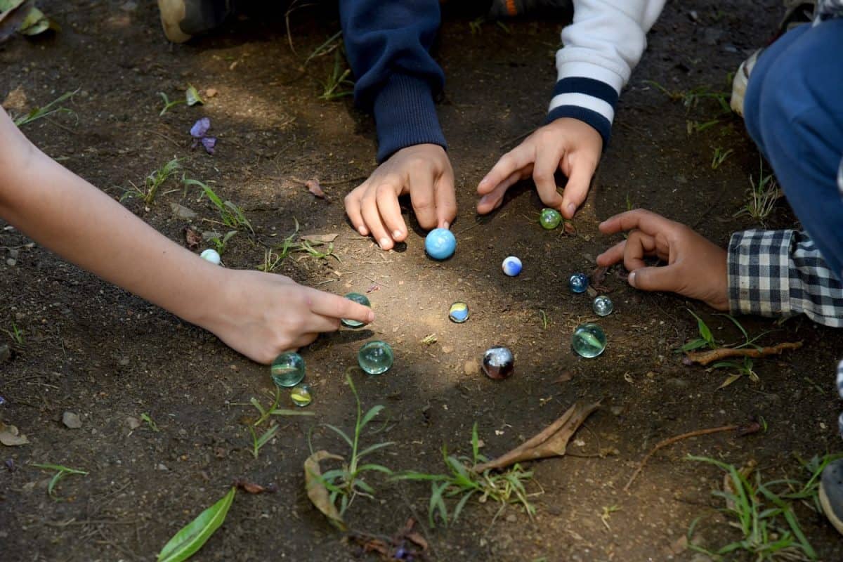 Boy playing with marbles on the sidewalk. retro game, having fun with marbles in the school yard at break time. Traditional game, shared section