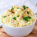 Fresh homemade traditional old-fashioned Amish Potato Salad with potatoes, boiled eggs, creamy dressing and celery in a white bowl on wooden background