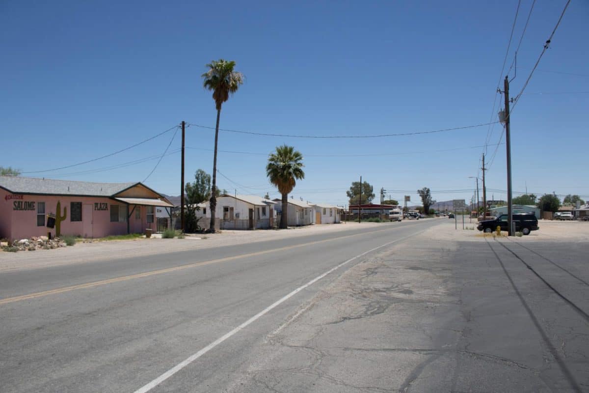 The lonely road on a hot summer town in Salome Arizona with palms and small white houses