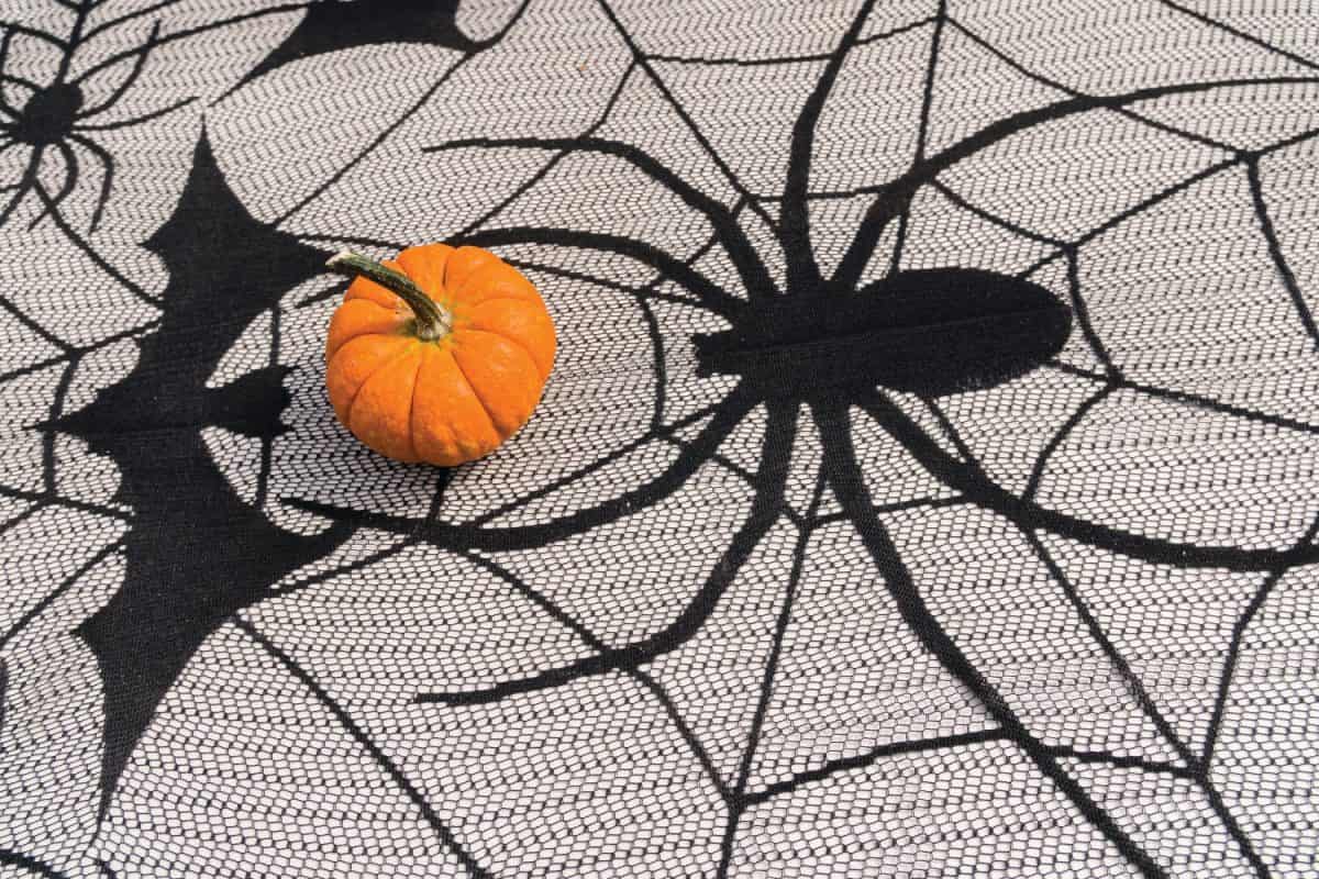 Halloween table cloth looks like a spider web with a mini pumpkin sitting on top