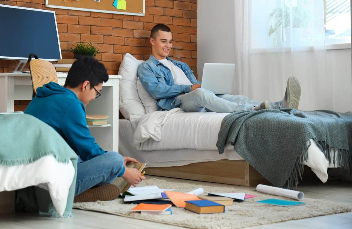 Male students doing homework in dorm room