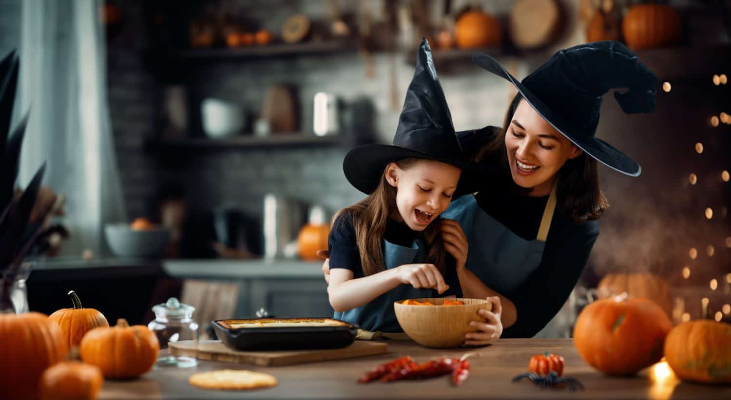 Mother and her daughter having fun at home. Happy Family preparing for Halloween. Mum and child cooking festive fare in the kitchen.