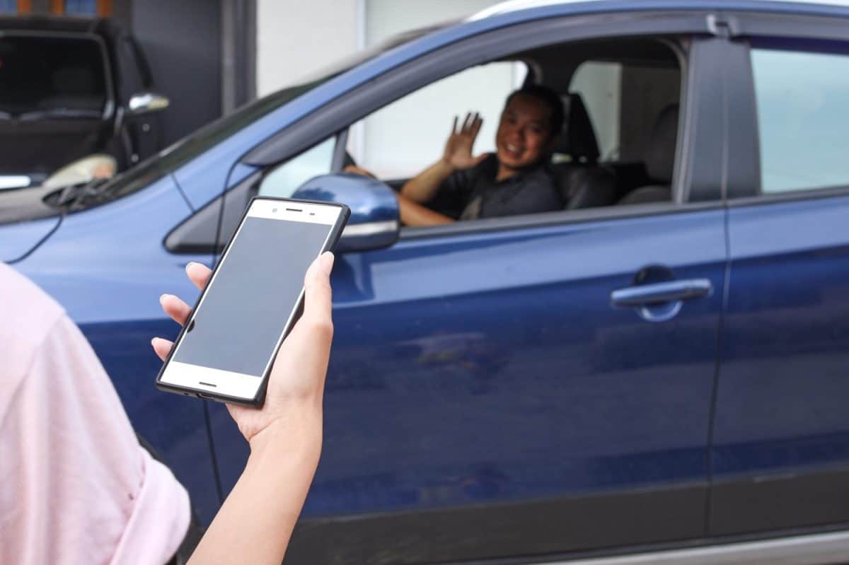 Customer waiting driver to pick up on city street. Mobile and online booking for rideshare transportation with cellphone.