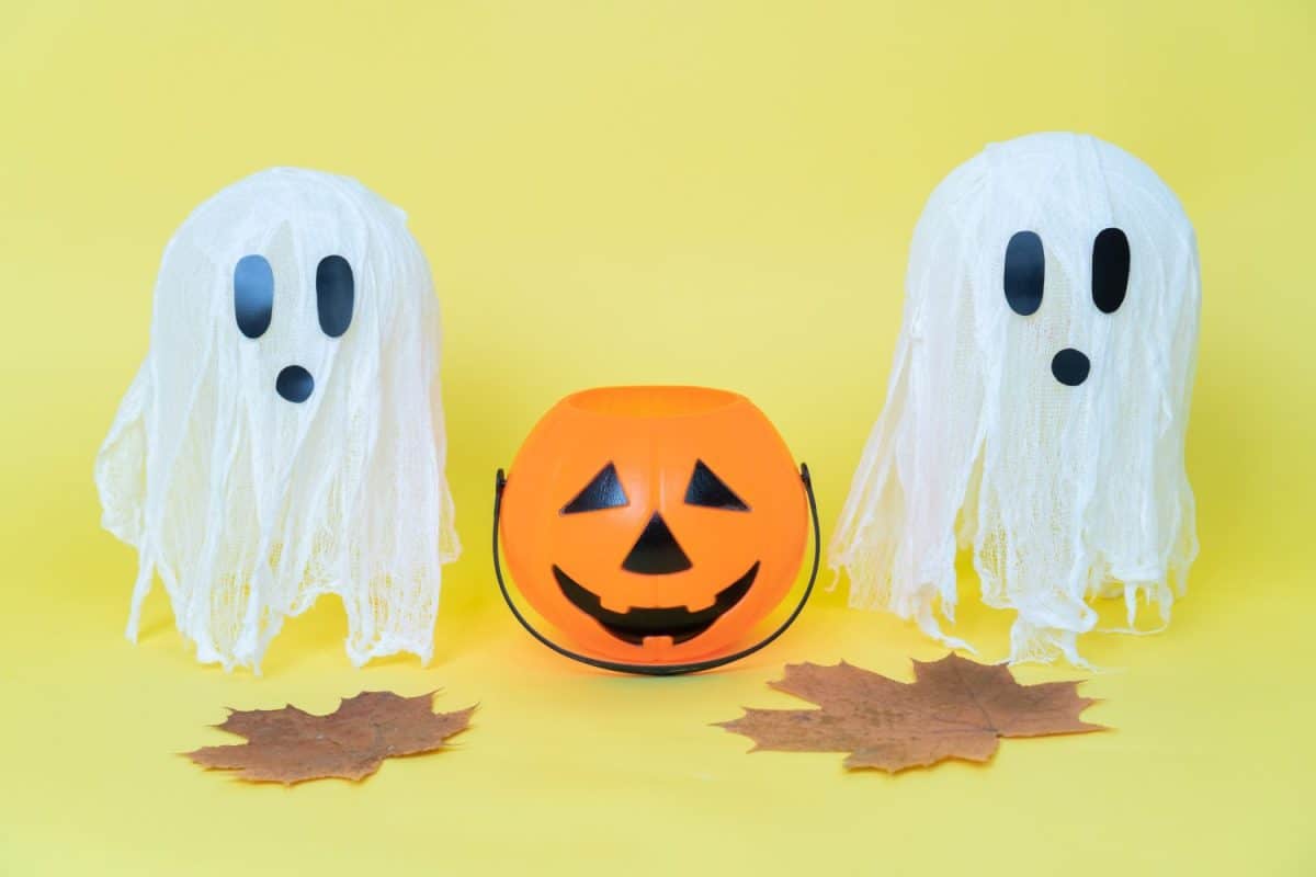 Halloween ghosts made from bandages, glue, water and using balloons and glasses on yellow orange background. Children's art project. DIY concept. Step by step 8. Halloween holiday concept.