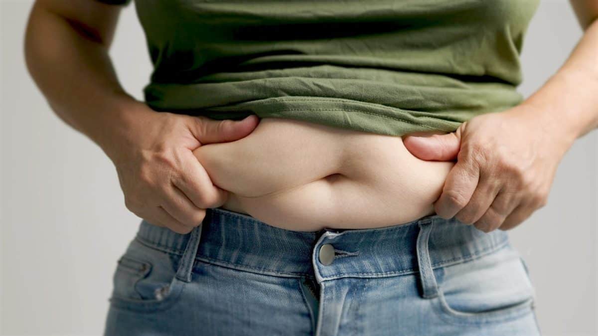 close up of woman hand pinching excessive belly fat