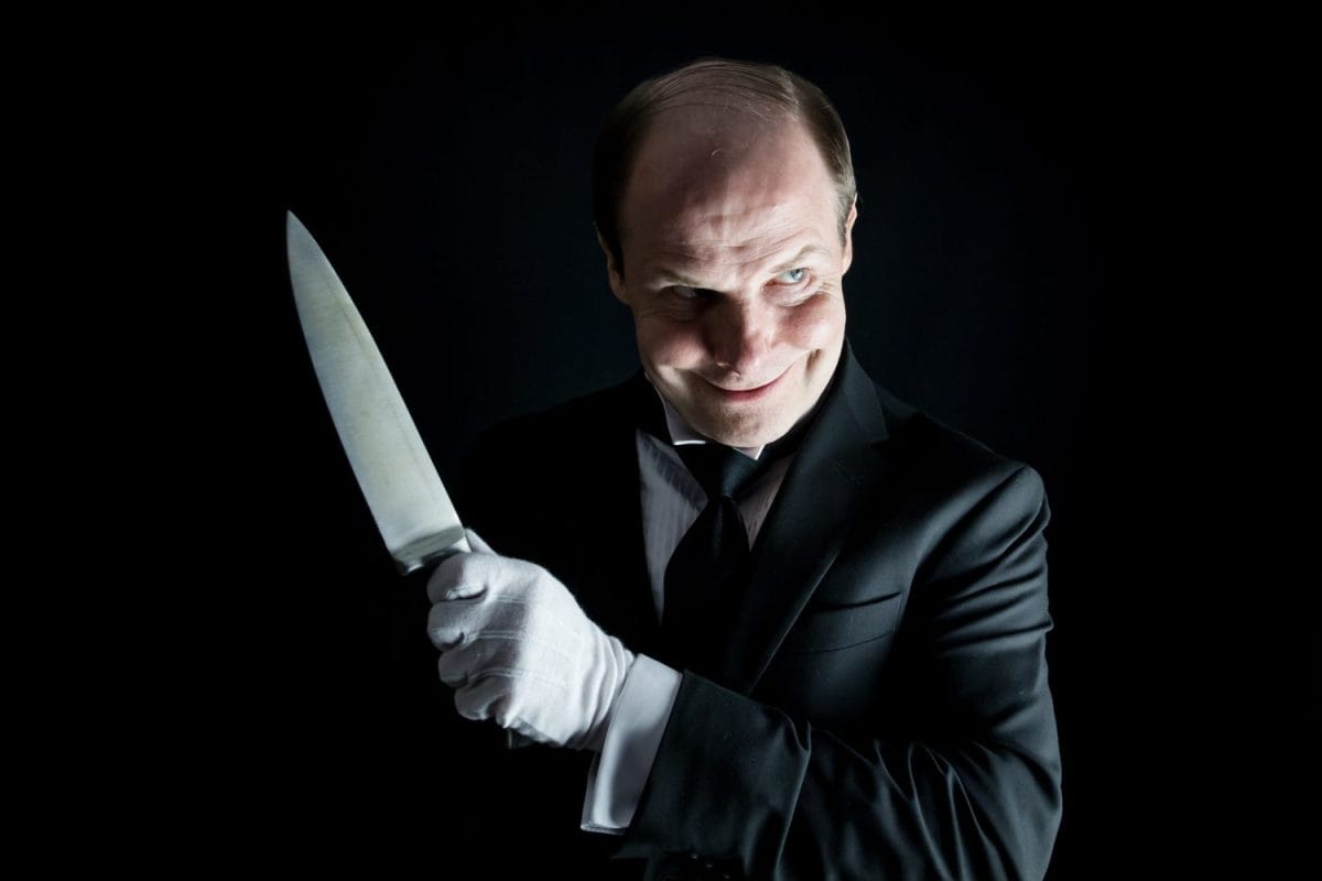 Butler in Dark Formal Suit and White Gloves Holding Sharp Knife. Concept of Butler Did It. Classic Murder Mystery.