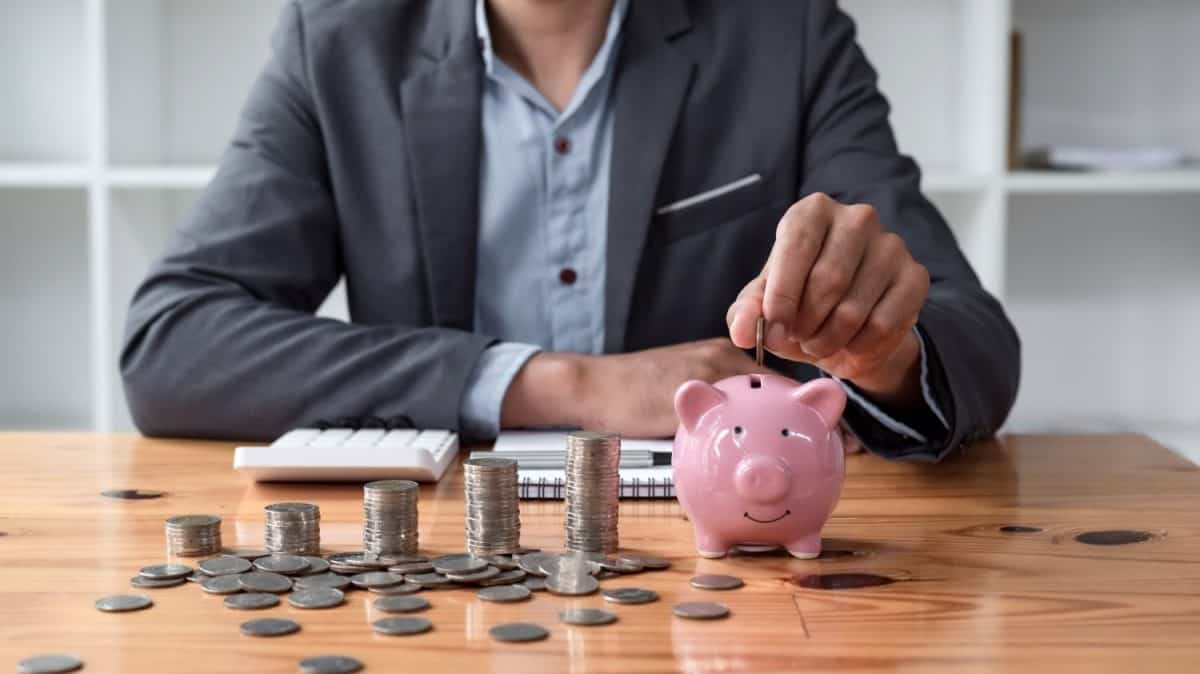 Businessman saving money with piggy bank and coins on desk, financial planning and investment concept.