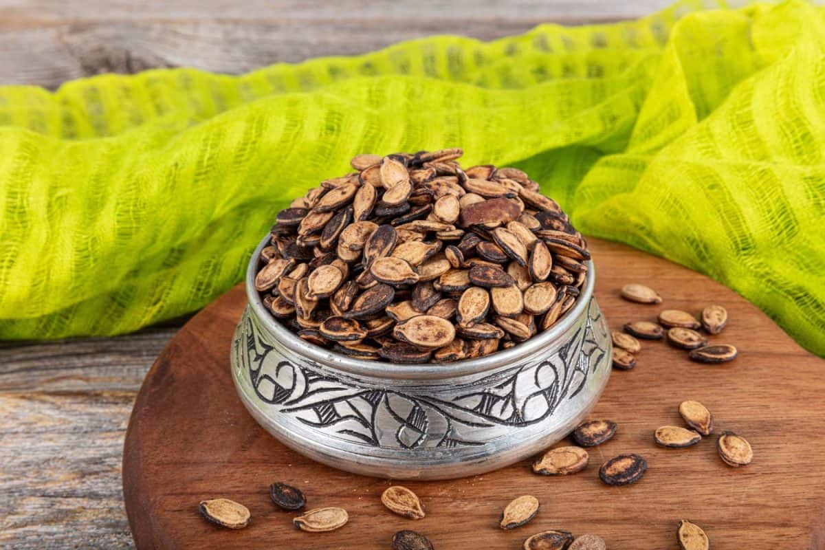 Roasted watermelon seeds in a copper pot. Fry the watermelon seeds and the snack is ready. Snack snack concept combined on a wooden background.