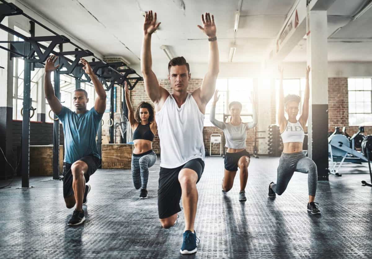 Friends, exercise and lunge in group at gym for workout, core fitness or training together indoors. Diverse class, people or warm up for ab muscle, session and sport for health challenge in gymnasium