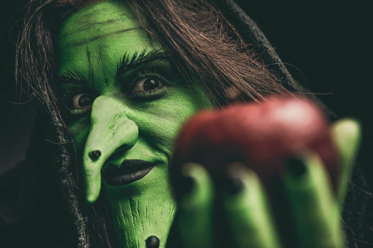 Green witch holding an apple in her hand. Shallow depth of field.