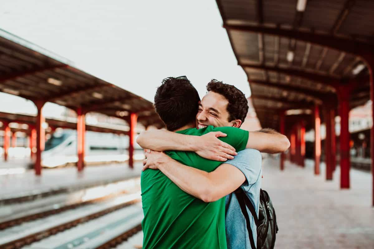 Two brothers on the platform waiting for the train. They meet again after a long time without seeing each other. Joy and hugs. Lifestyle. Travel photography