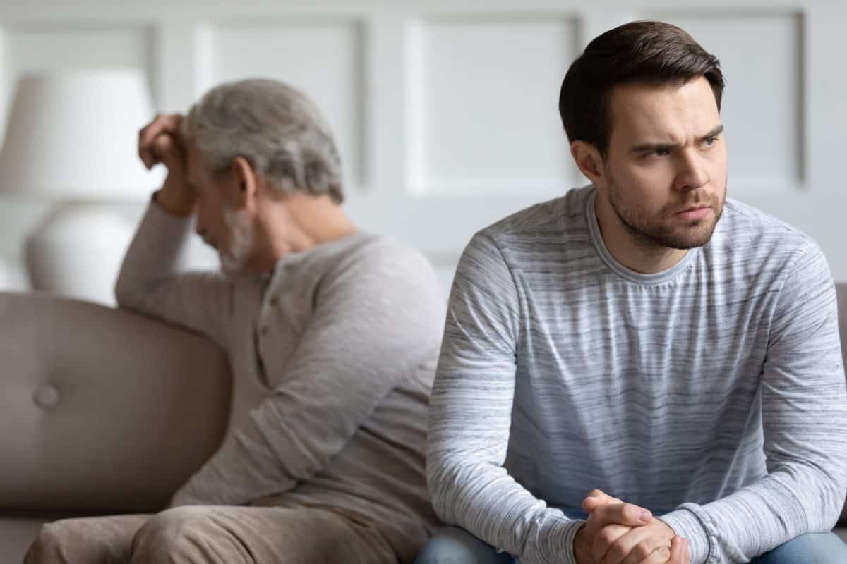 Mad thoughtful young man sit separately having fight misunderstanding with elderly father, angry stubborn mature dad and grown-up adult son avoid talking after quarrel, generation gap concept