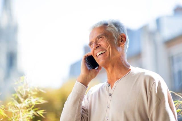 Close up portrait happy older man talking with mobile phone outside