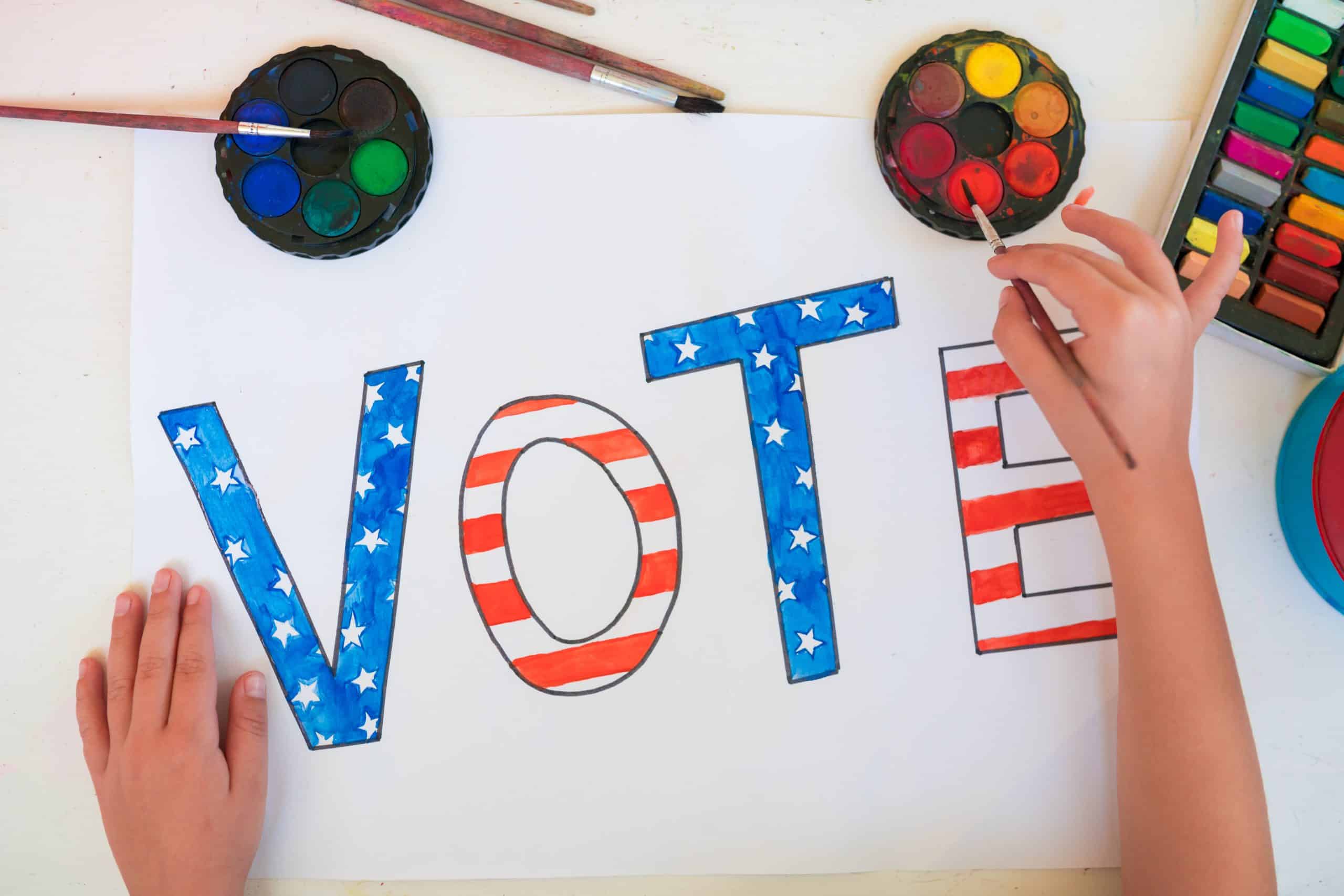 Close-up of a child girl drawing the word Vote