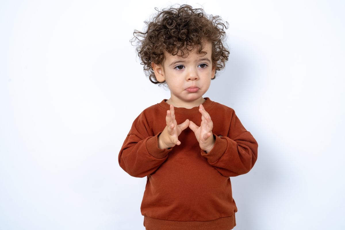 Beautiful two year old toddler with curly hair wearing casual clothes over white studio background feeling sad about to cry.