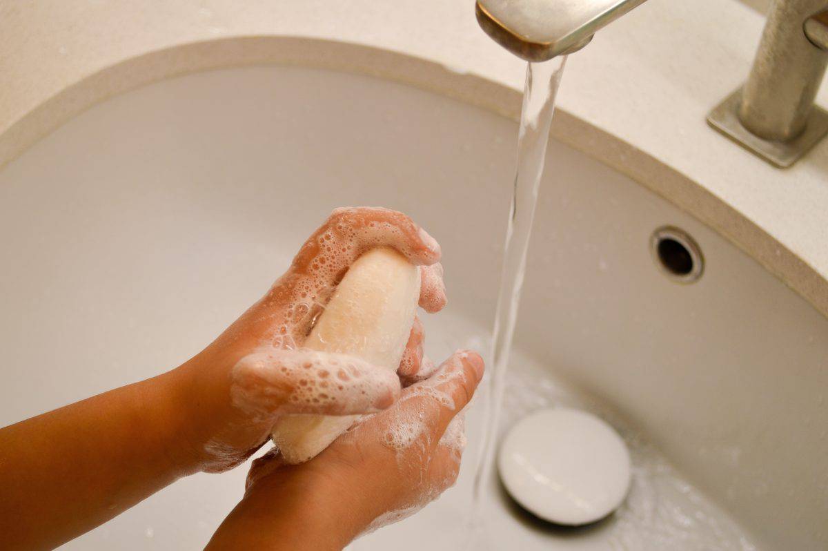 A child's hands are being washed with soap under a running tap, emphasizing the importance of hygiene. This image highlights the practice of proper hand washing for children.