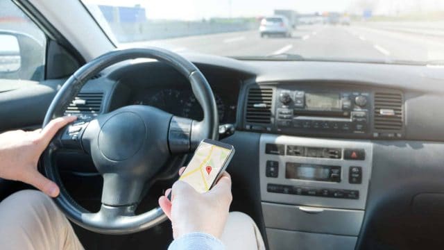 Distracted driver looking at GPS on phone.