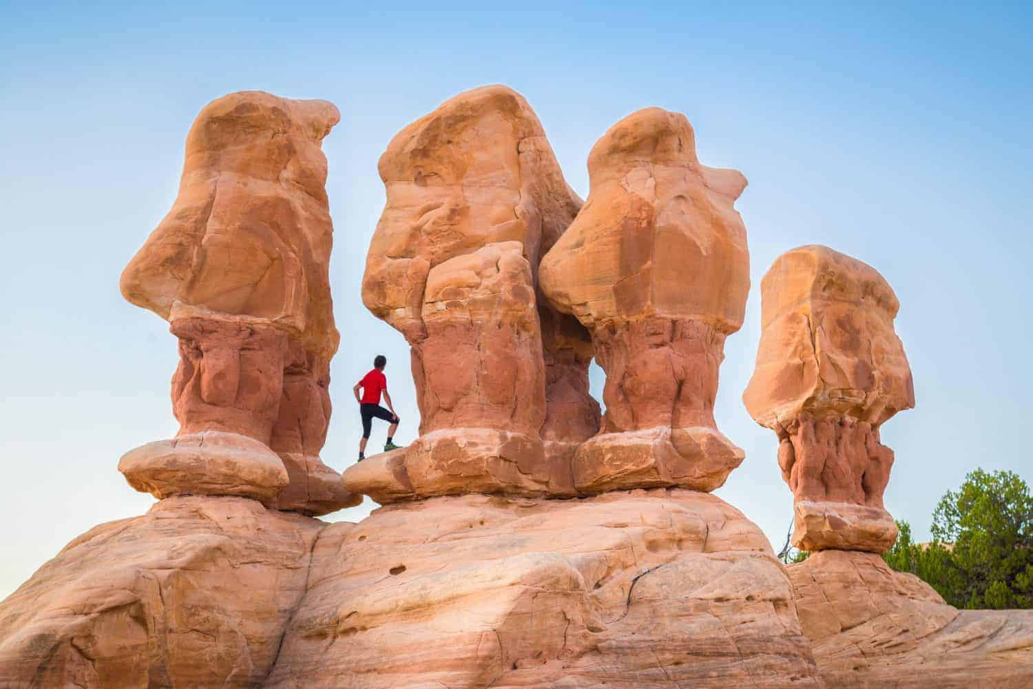 Beautiful view of male hiker standing between amazing Four Hoodoos sandstone formations in Devil's Garden in beautiful evening light at sunset, Grand Staircase-Escalante National Monument, Utah, USA