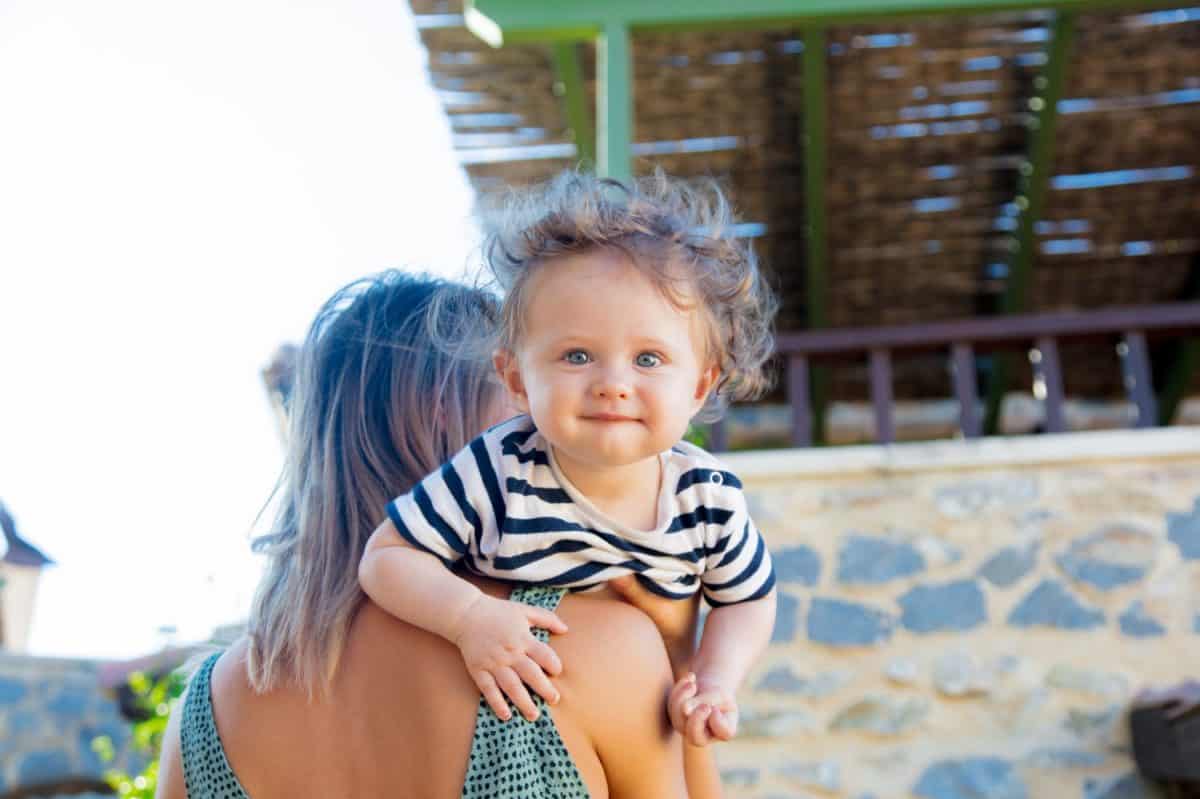 Young mother with a child on little greek village street, Crete, Greece