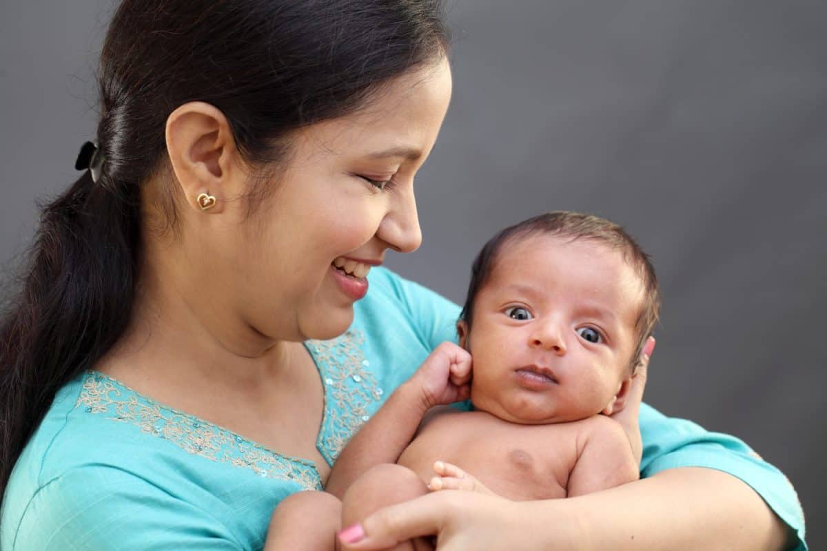 Cheerful mother playing with newborn baby