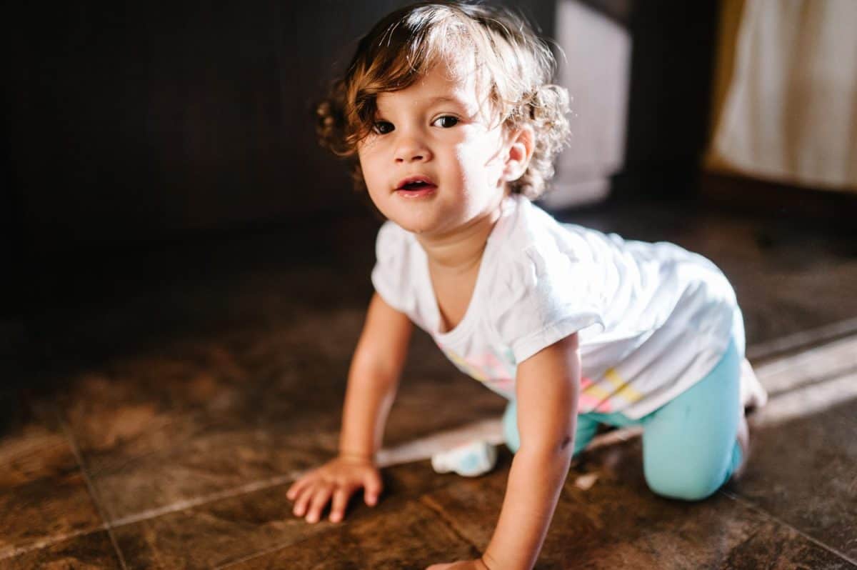 Portrait of a toddler, girl, adorable baby playing and crawling on the floor indoors, little child play, game in a room at home or kindergarten.