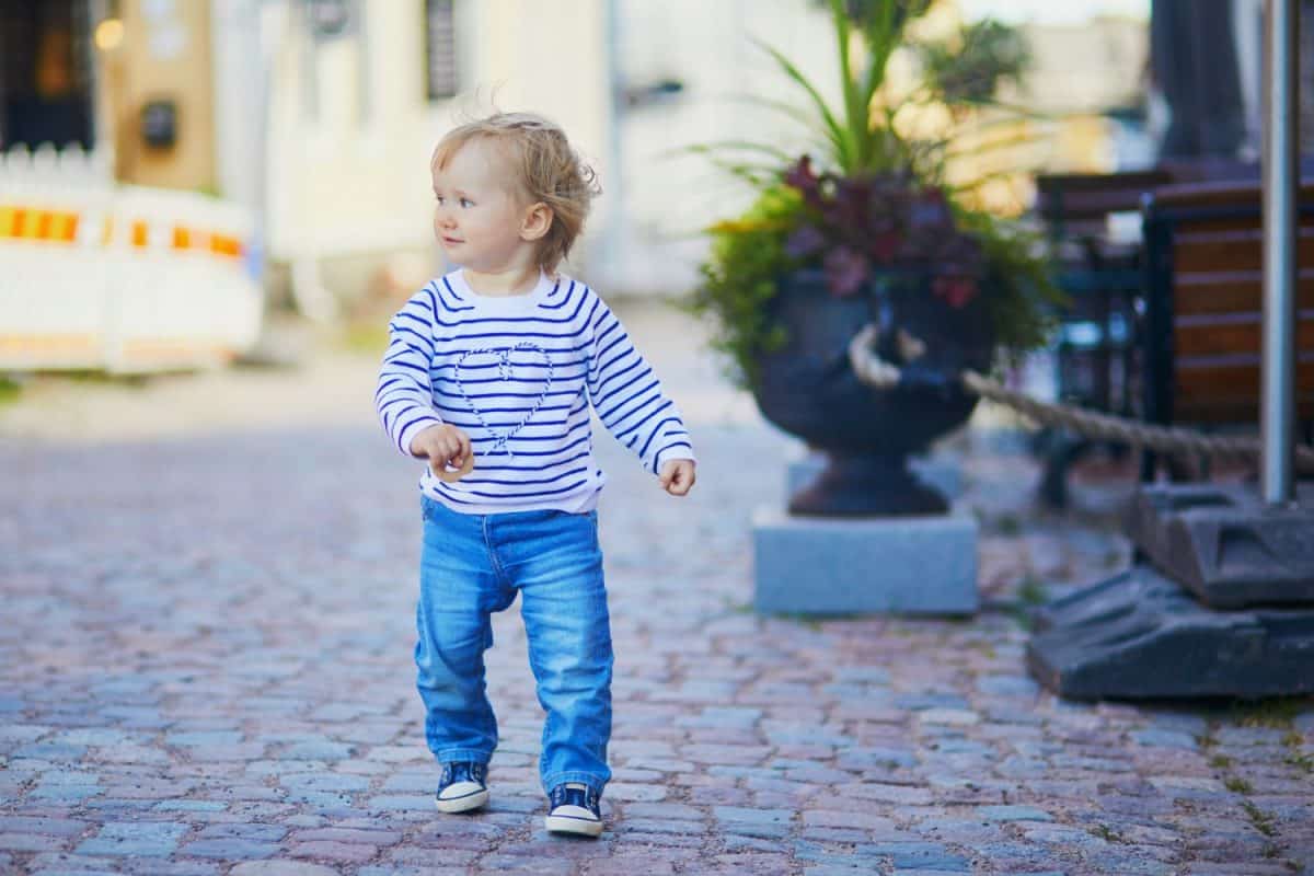 Happy smiling toddler walking in the street of Finnish town Porvoo, Finland