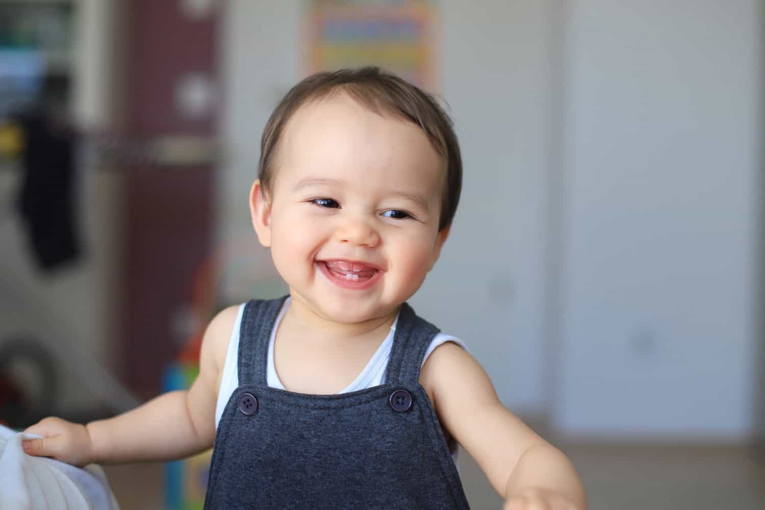 Cute baby boy smiling with first milk teeth. Mixed race Asian-German infant about 9-10 months old laugh face. Healthy newborn child.