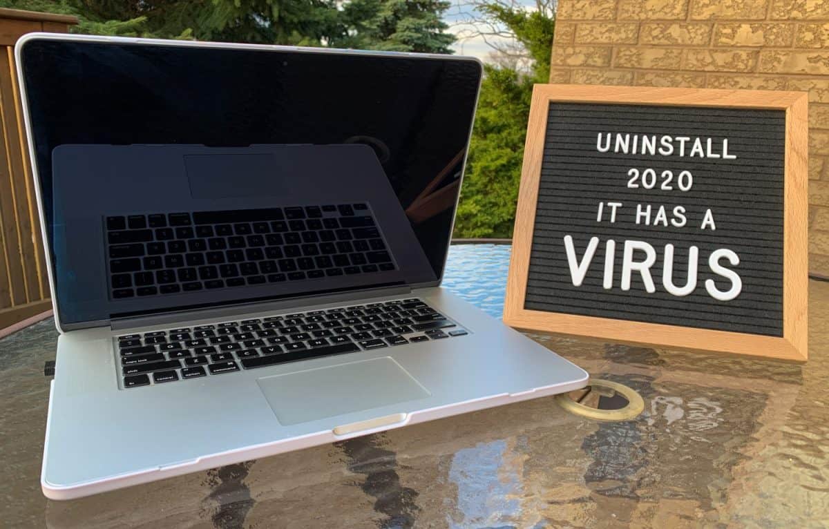 Photo of a felt letter board sign with a virus joke or meme for covid-19 / coronavirus pandemic on it. Placed beside a laptop when working from home. White letters.