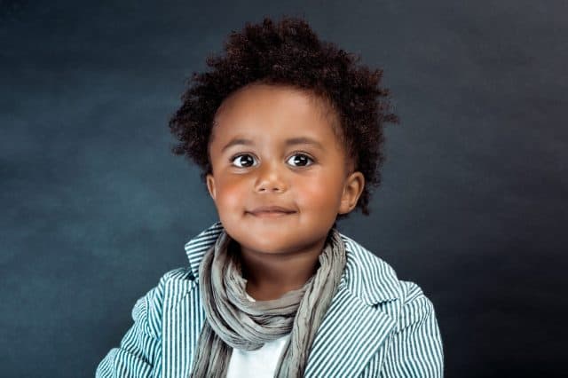 Studio Portrait of a Stylish Little African-American Boy with Curly Hair Isolated on Dark Background. Kids Fashion. Kids Clothes.