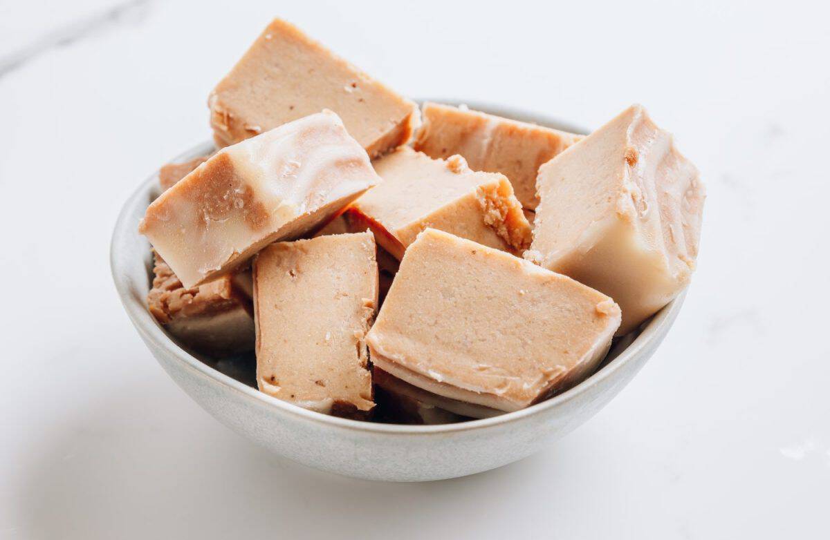 Raw vegan peanut butter fudge on a white marble background. Healthy vegan food concept. Selective focus